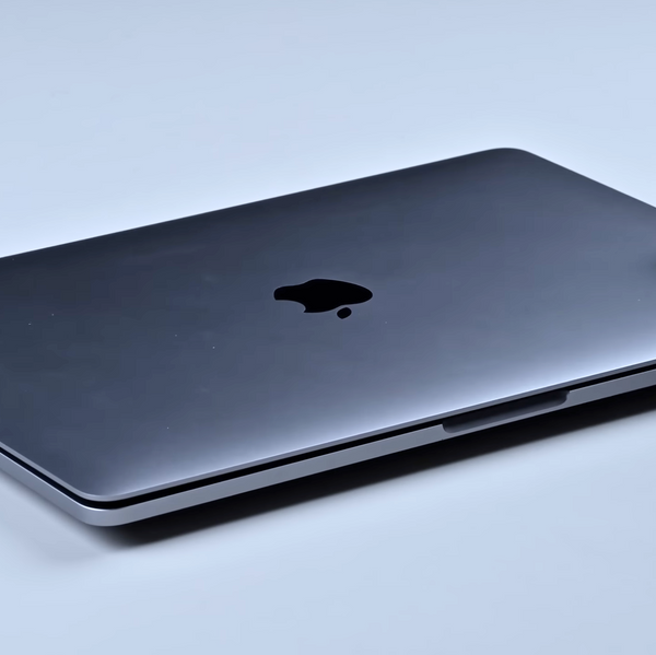 macbook laptop sitting on a table top, unable to be fully closed due to the expanded swollen battery pushing the trackpad up and the bottom cover down