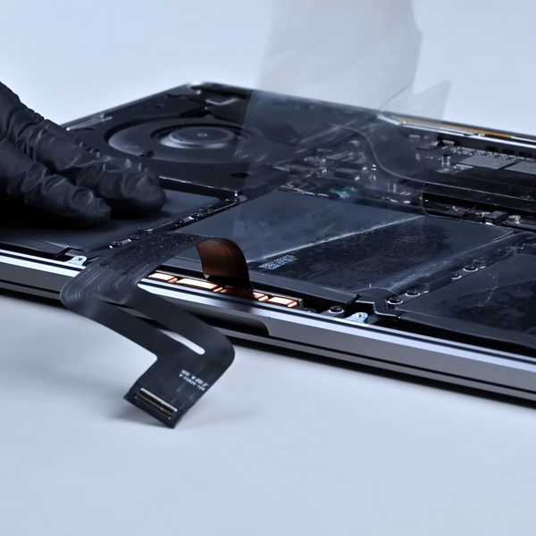open macbook laptop, technician removing protective film from the newly installed battery